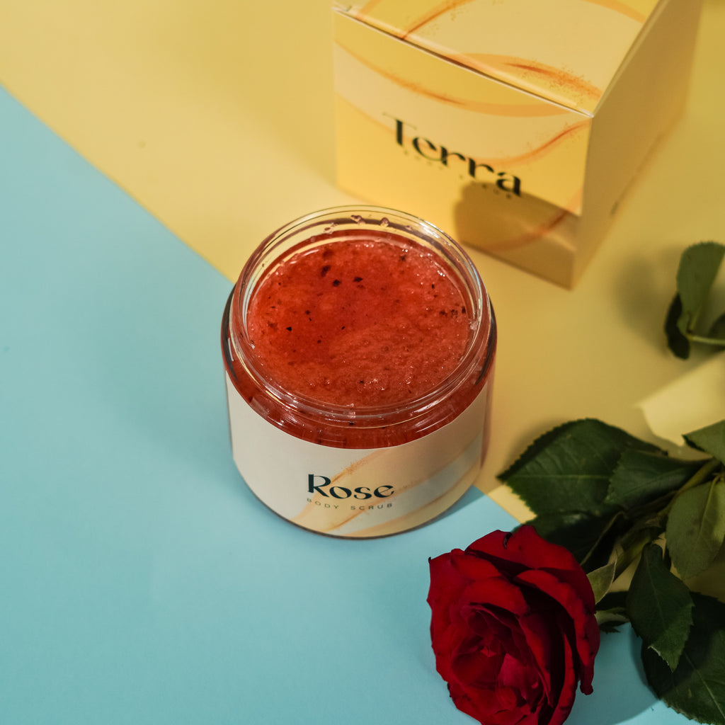Jar of 'Rose' scrub with a box labeled 'terra' on a yellow and blue background.