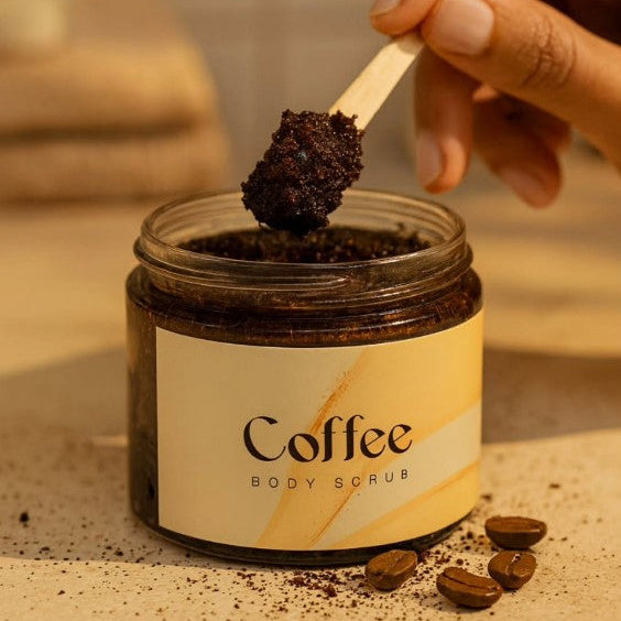 Jar of coffee body scrub with a wooden spoon and scattered coffee beans on a neutral background.