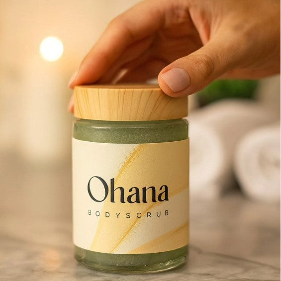 Jar of Ohana bodyscrub with a hand holding the lid, on a neutral background.