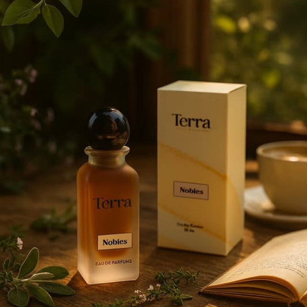 Terra Nobies perfume bottle and packaging on a wooden surface with plants and a cup in the background.